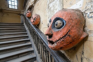 Intriguing carved faces adorn a weathered staircase in an old building.