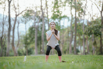 Young Asian woman practicing yoga in a quiet park, gracefully in a relaxed pose, relaxing and...