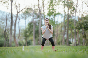 Young Asian woman practicing yoga in a quiet park, gracefully in a relaxed pose, relaxing and...