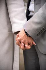 A close-up captures a tender moment as a couple's hands are intimately intertwined, showcasing their connection and affection.