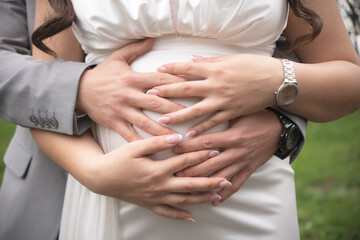A loving couple's hands gently embrace the woman's pregnant belly, symbolizing their anticipation and care for their unborn child.
