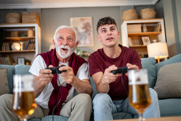Grandfather and grandson playing videogames and drinking beer at home