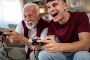 Grandfather and grandson playing videogames and having fun © Migma_Agency
