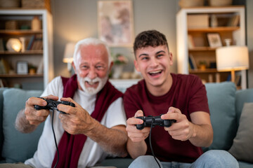 Grandfather and grandson playing videogames on sofa at home