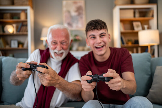 Grandfather and grandson playing videogames on sofa at home
