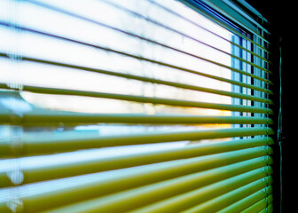 Look through blinds on sunrise. Green Blinds to secretly look through window. Bedroom window, opening curtains. Looking through window blinds, morning sun light coming inside of room. Windowshade.