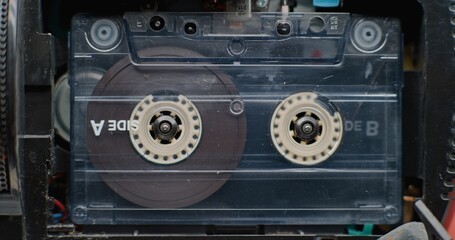 Vintage Audio Cassette Tape Playing Music or Analog Sound On Cassette Player. Playback of Mixtapes Using Retro Hi-Fi Audio Equipment with Old School Vibe. Reel-to-Reel Tape Recorder. Macro Close Up.