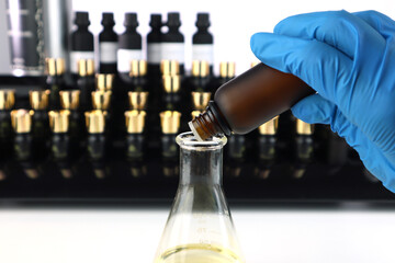 essential oil glass bottle is used to blend nice scent for making perfume and candle by perfumer in the laboratory with background of blotting paper , fragrance bottle , essential oil bottle and flask