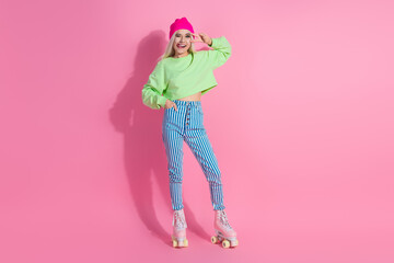 Young woman in a colorful outfit roller skating against a pink background, showcasing a joyful and vibrant lifestyle