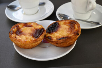 Pastéis de nata dans une soucoupe à côté de tasses d'expresso