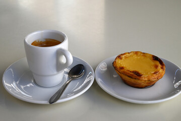 Pastéis de nata dans une soucoupe à côté d'une tasse d'expresso