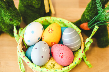 Colorful Easter eggs in a basket surrounded by decorative bunnies on a festive table