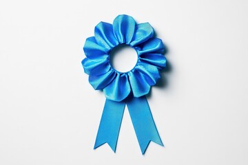 A blue rosette ribbon award laying on a white background