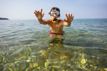 Boy dives and swims in the sea with the equipment. He has diving mask, snorkel and fins.