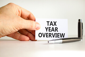 Tax year overview symbol. Concept words Tax year overview on beautiful white card. Beautiful white background. Businessman hand. Business tax year overview concept. Copy space.