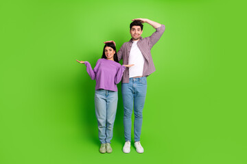 Young couple posing against green background humorously showcasing height difference