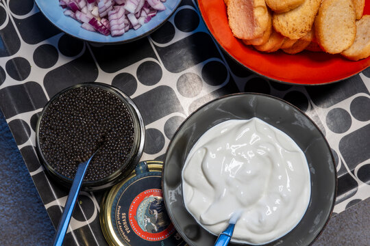 Stockholm, Sweden Imported Black Aea caviar in a bowl with cream, onions and crackers.