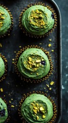 Fototapeta premium Vegan and Gluten-Free Lemon Blueberry Pistachio Cupcakes. Delicious green pistachio cupcakes on dark tray for dessert inspiration