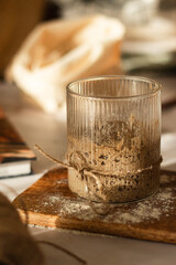 Active sourdough starter in a glass. Rye leaven for bread and kitchen wooden utensil on rustic background. Traditional bread baking concept. Close-up. Selective focus. Blurred background.