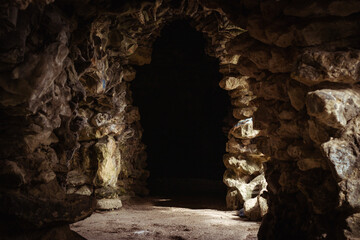 A stone cave with dark tunnels and narrow passages. A natural underground structure with jagged...