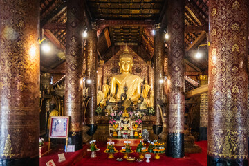 A Serene Buddha Statue is Surrounded by Beautiful Offerings in an Ornate Temple Structure, Luang Prabang, Laos