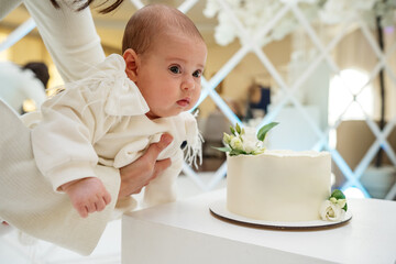 A minimalist white wedding cake with a smooth buttercream finish, adorned with delicate white...