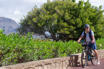 Happy active cyclist senior man wearing helmet enjoys a beautifulsunny day outdoors with his bike....