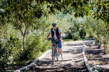 Happy active cyclist senior man wearing bicycle helmet enjoys a beautiful day outdoors. Smiling...