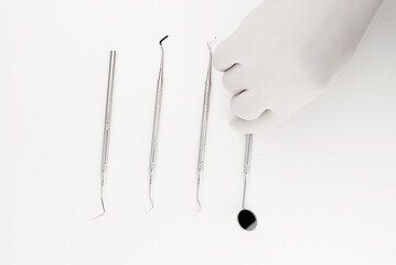 Dental Tools Arranged on White Background with Gloved Hand in Frame..