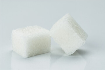 Two White Sugar Cubes Standing Together on a Light Background..