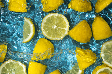 Juicy lemon background of halves and slices of fresh lemons in water.