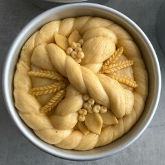 Unbaked traditional Ukrainian Easter bread with symbolic dough decoration in baking forms