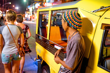 Night Street Scene with People and a Colorful Hat by a Rickshaw..