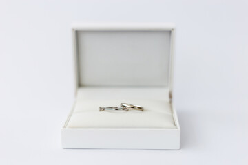 A pair of elegant wedding rings is showcased in a luxurious jewelry box against a clean, minimalist...