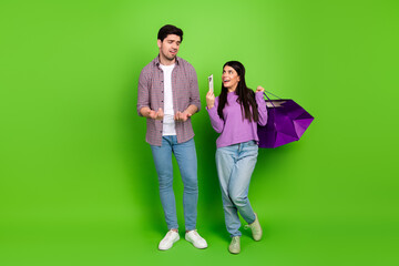 Fototapeta premium Young couple enjoying a shopping experience while bonding together on a vibrant green background showcasing joyful emotions