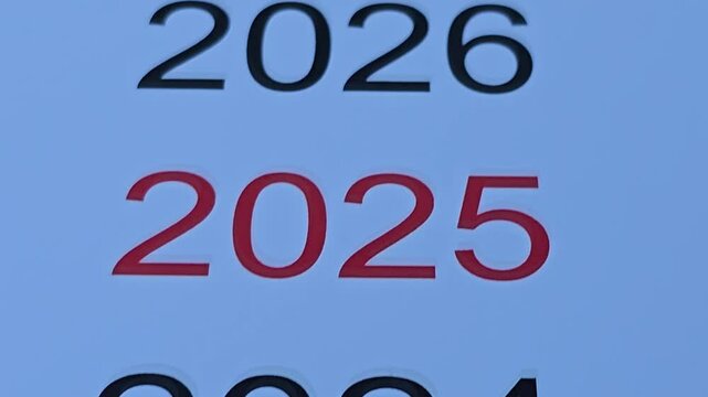Bold numbers representing upcoming years are arranged vertically on white paper. Each year is clearly visible, showcasing a range from 2019 to 2027, with 2025 standing out in red
