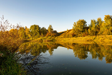 River landscape on a sunny autumn morning. The serenity and tranquility of an autumn morning on the banks of a narrow rural river.