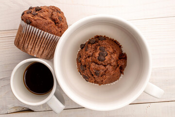 Chocolate muffins with coffee and kitchen utensils, close-up, top view.