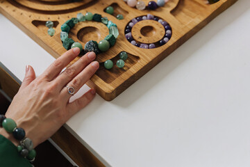 Jewelry maker assembling natural stone bracelets. Handmade beaded bracelet workshop with gemstones. Crafting spiritual gemstone jewelry. Natural stone.