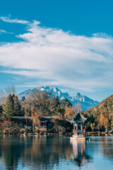 Fototapeta premium Photograph of Black Dragon Pool with Jade Dragon Snow Mountain and bridge in Lijiang