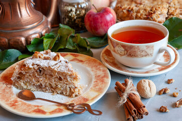 Slice of Homemade apple pie with walnuts, cinnamon and hot tea drink.