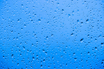 Photograph of raindrops on a glass surface reflecting and distorting a vibrant and colourful background capturing the beauty of light and water and sunlight.