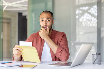 Portrait of upset worried man inside office, employee received letter with bad and sad news in...