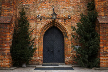 Historic brick church entrance framed by evergreen trees in Warsaw.