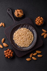 Peeled pine nuts in a bowl on a dark concrete background