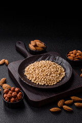 Peeled pine nuts in a bowl on a dark concrete background