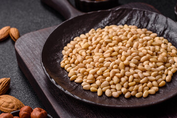 Peeled pine nuts in a bowl on a dark concrete background