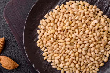 Peeled pine nuts in a bowl on a dark concrete background