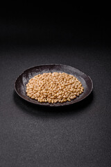 Peeled pine nuts in a bowl on a dark concrete background