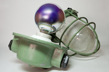 vintage pendant industrial lamp light, mine lamp, globe silvery lamp installed in white ceramic lamp holder. large green housing, protective explosion proof clear cover